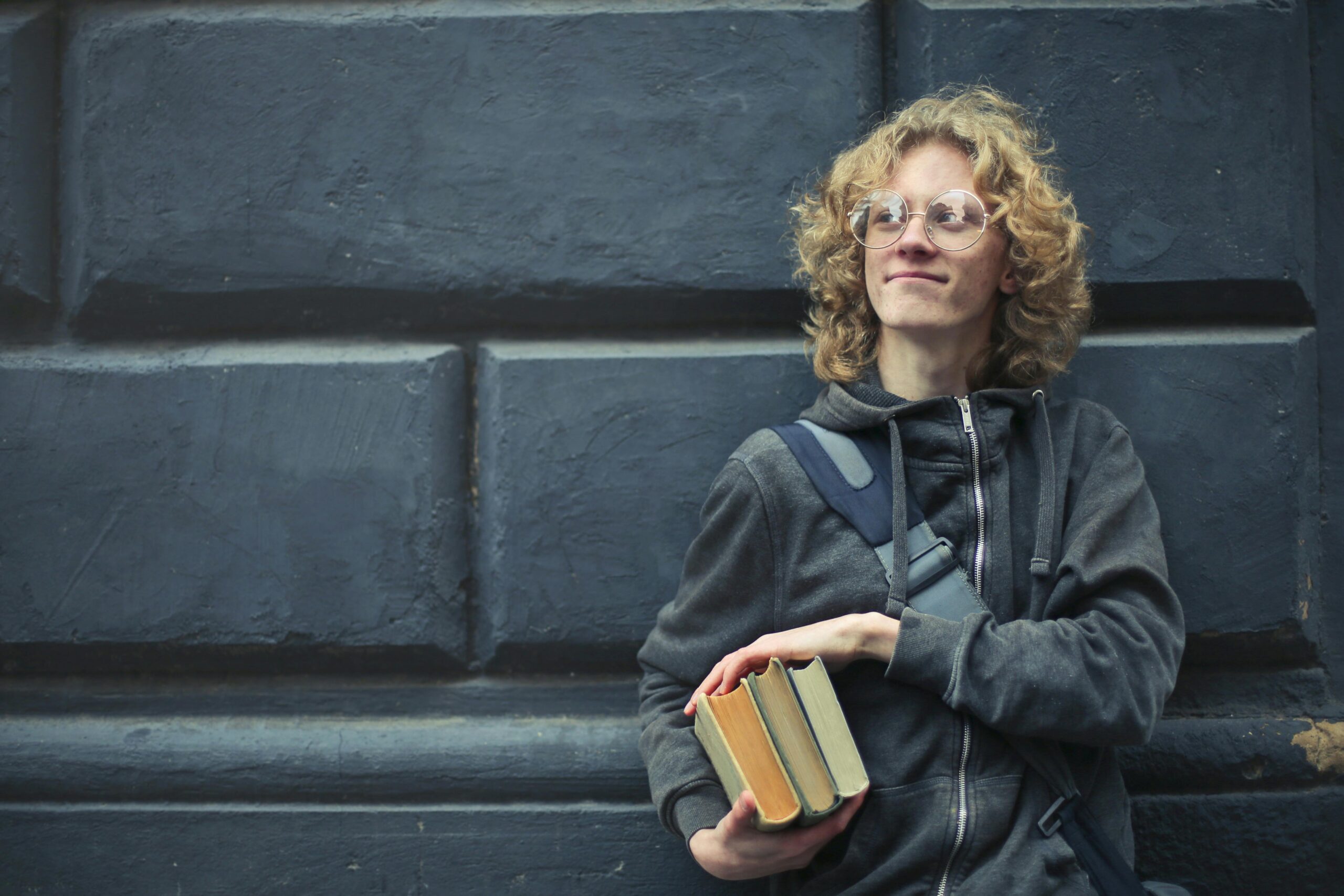 Junger Mann, Der An Die Wand Lehnt Und B&uuml;cher H&auml;lt